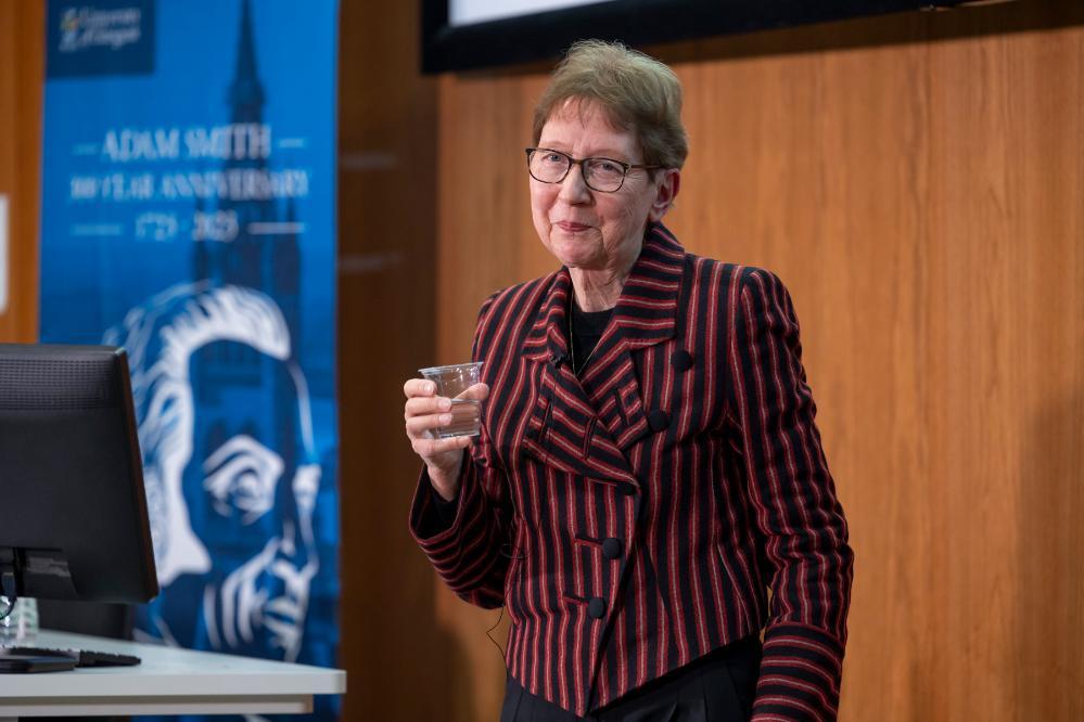 Christel Fricke holding a cup of water during her talk behind her is an Adam Smith banner Source: Charlotte Morris