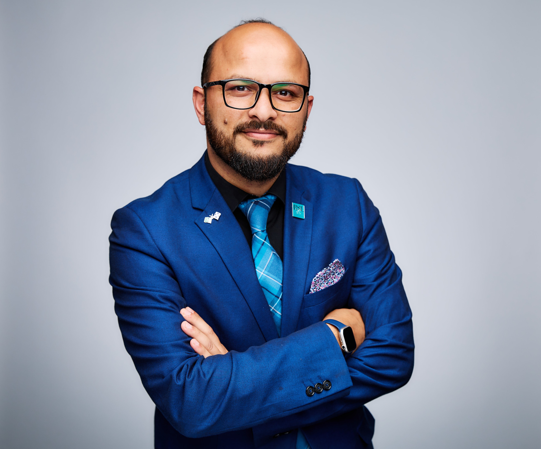 Professor Qammer Abbasi stands with arms crossed in a shiny blue suit