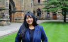 A student in a dark blue blazer standing in the courtyard of the University of Glasgow