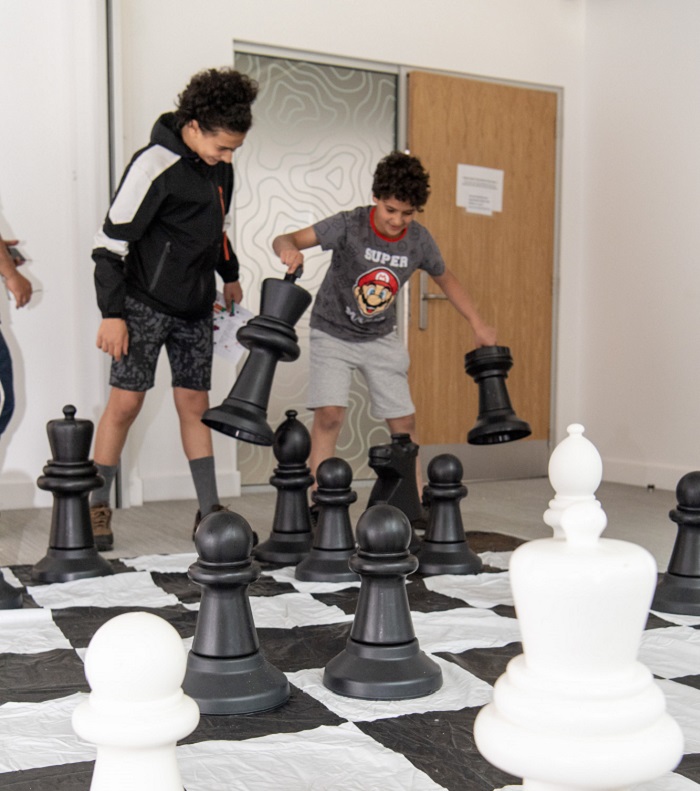 Two children play giant chess on our Byres Community Hub Day 2024