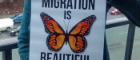 Alison Phipps holding MIGRATION IS BEAUTIFUL poster featuring a monarch butterfly