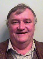 photo of professor Dudley Knowles: an older heavier man with dark hair starting to grey, collared shirt and vest, smiling wide at the camera