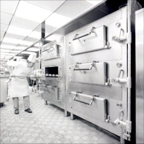 A chef using the bread oven in the Galley.