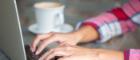 Photo of laptop, coffee cup and hands