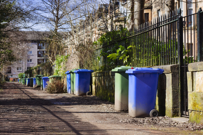 Wheelie bins (blue for recycling, green for general refuse) lined up for collection in a Glasgow alley. 768x512px
