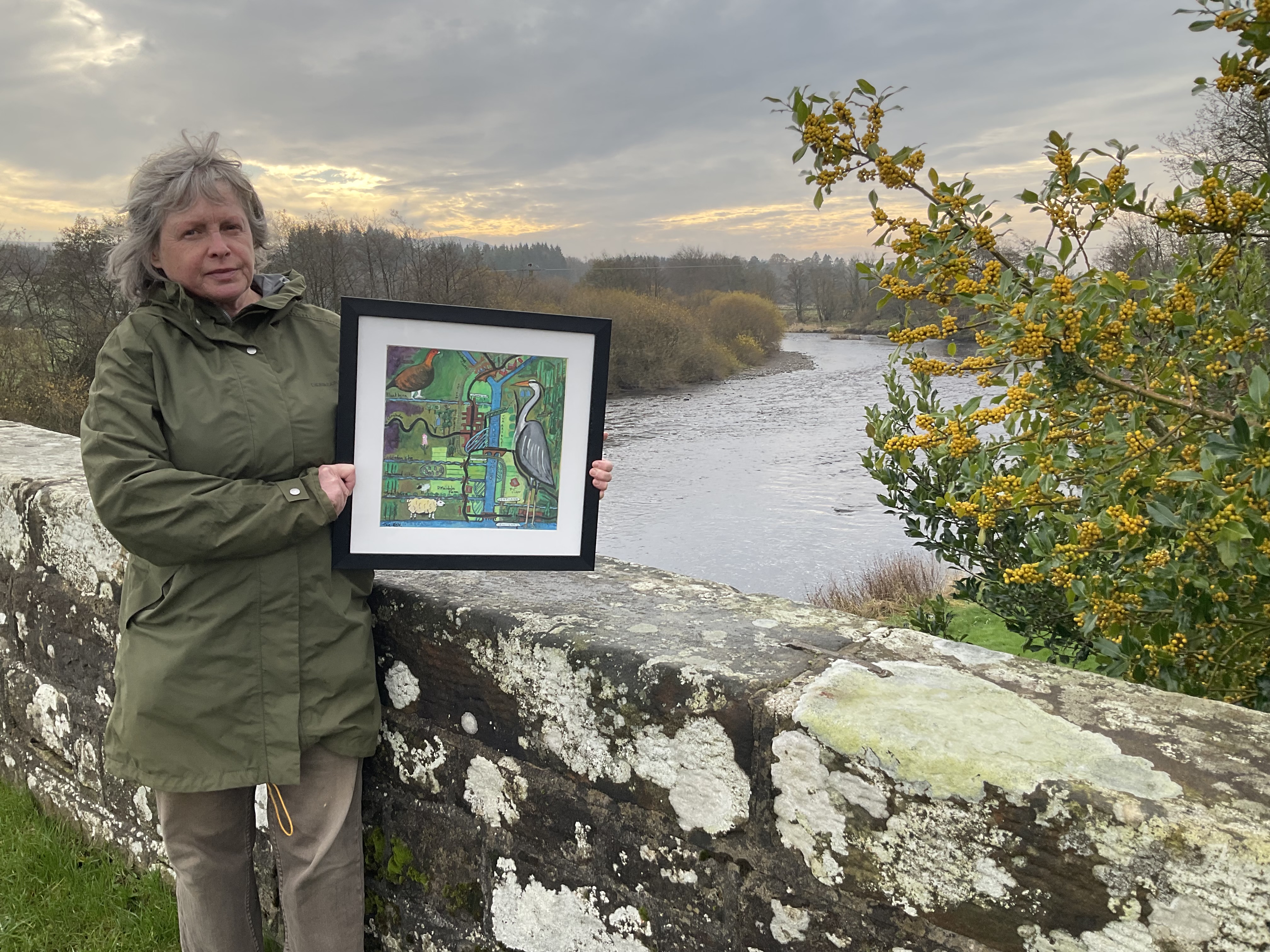 Woman holding artwork next to river