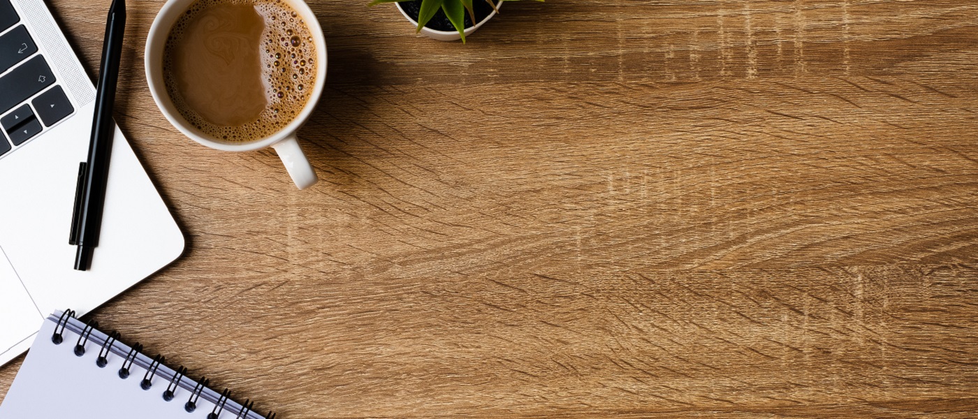 Photo of a wooden table with coffee notepad and pen